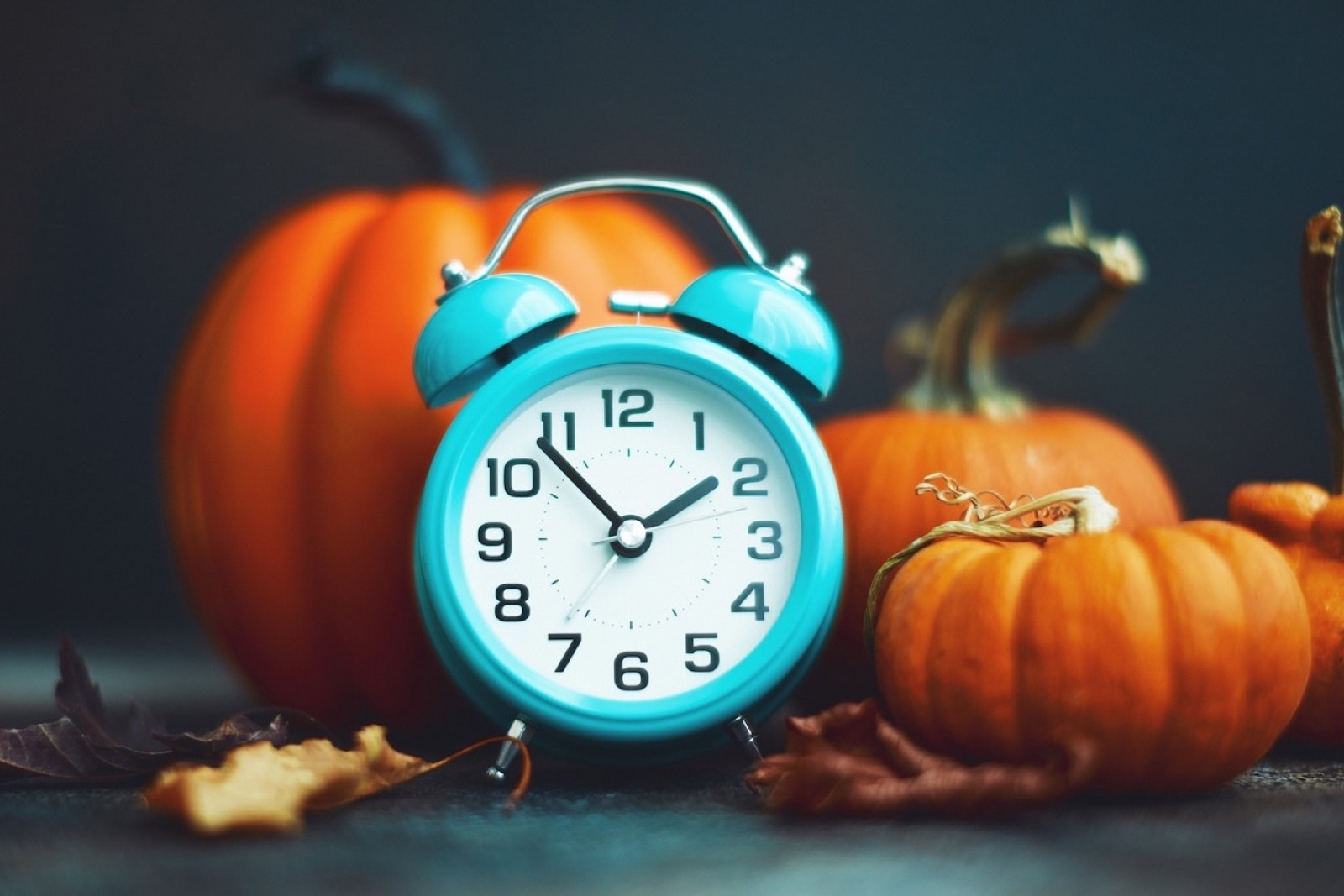 Reloj despertador entre calabazas, referencia al fin del horario de verano 2026
